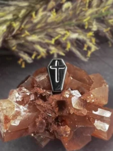 Titanium threadless coffin‑shaped end with engraved cross displayed on reddish crystal cluster.