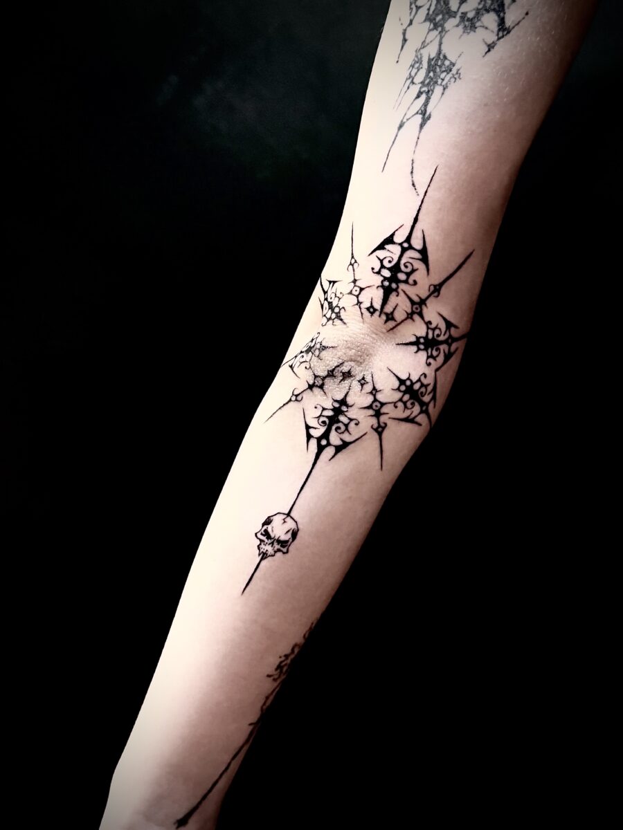 A tattoo of gothic ironwork framing an elbow. Tattooed by Dio