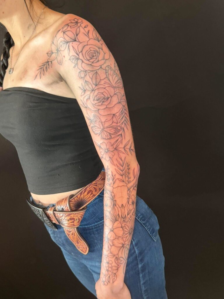 Fine line floral sleeve tattoo by Eric at Broken Clover Tattoo in Tucson, featuring roses, butterflies, flowers and botanical details.
