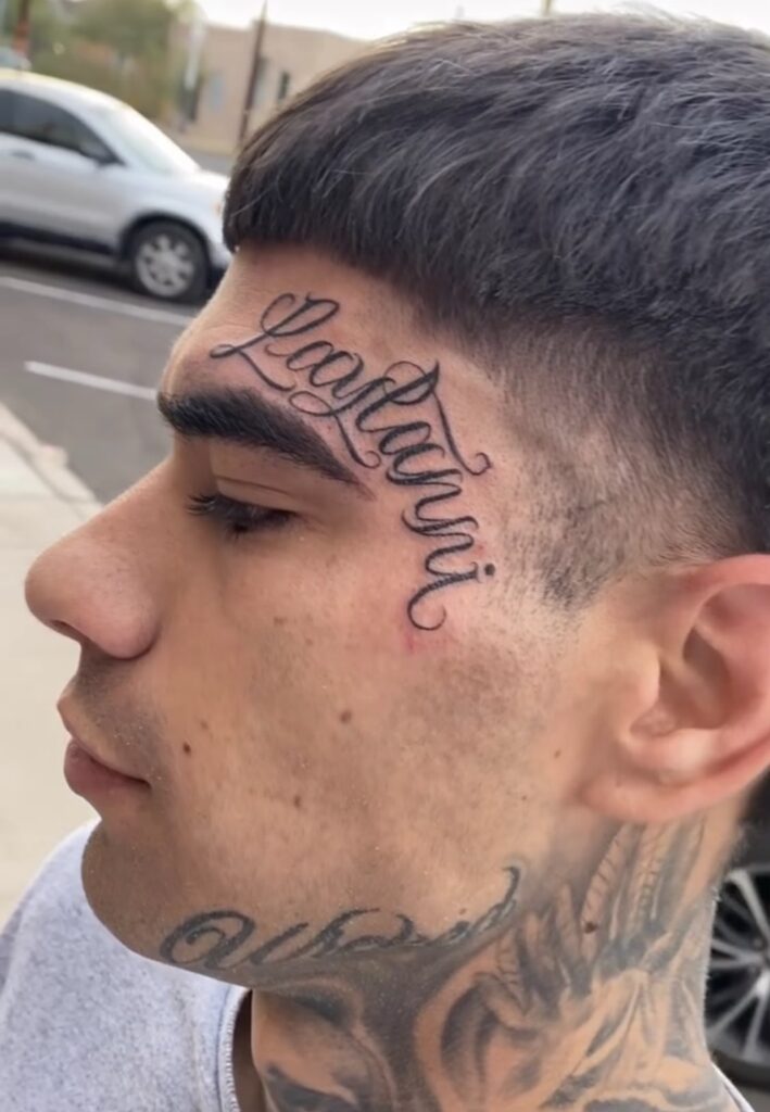 Hand-drawn script tattoo flowing across the temple and face