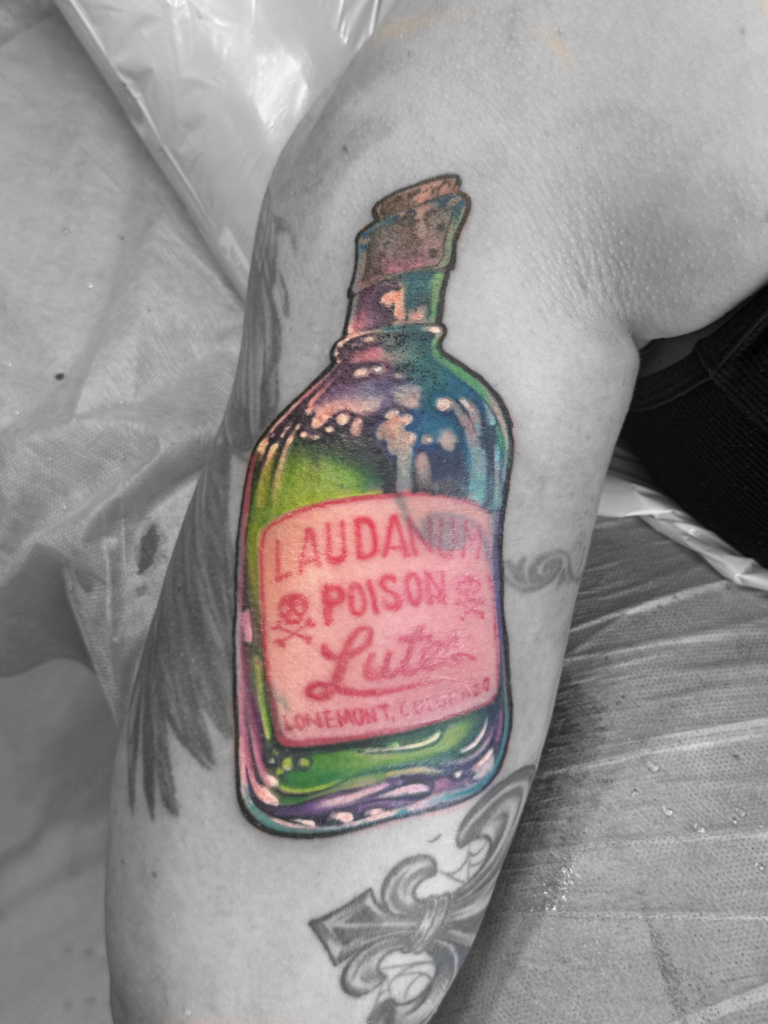 A tattoo of a labeled bottle of green and purple poison.